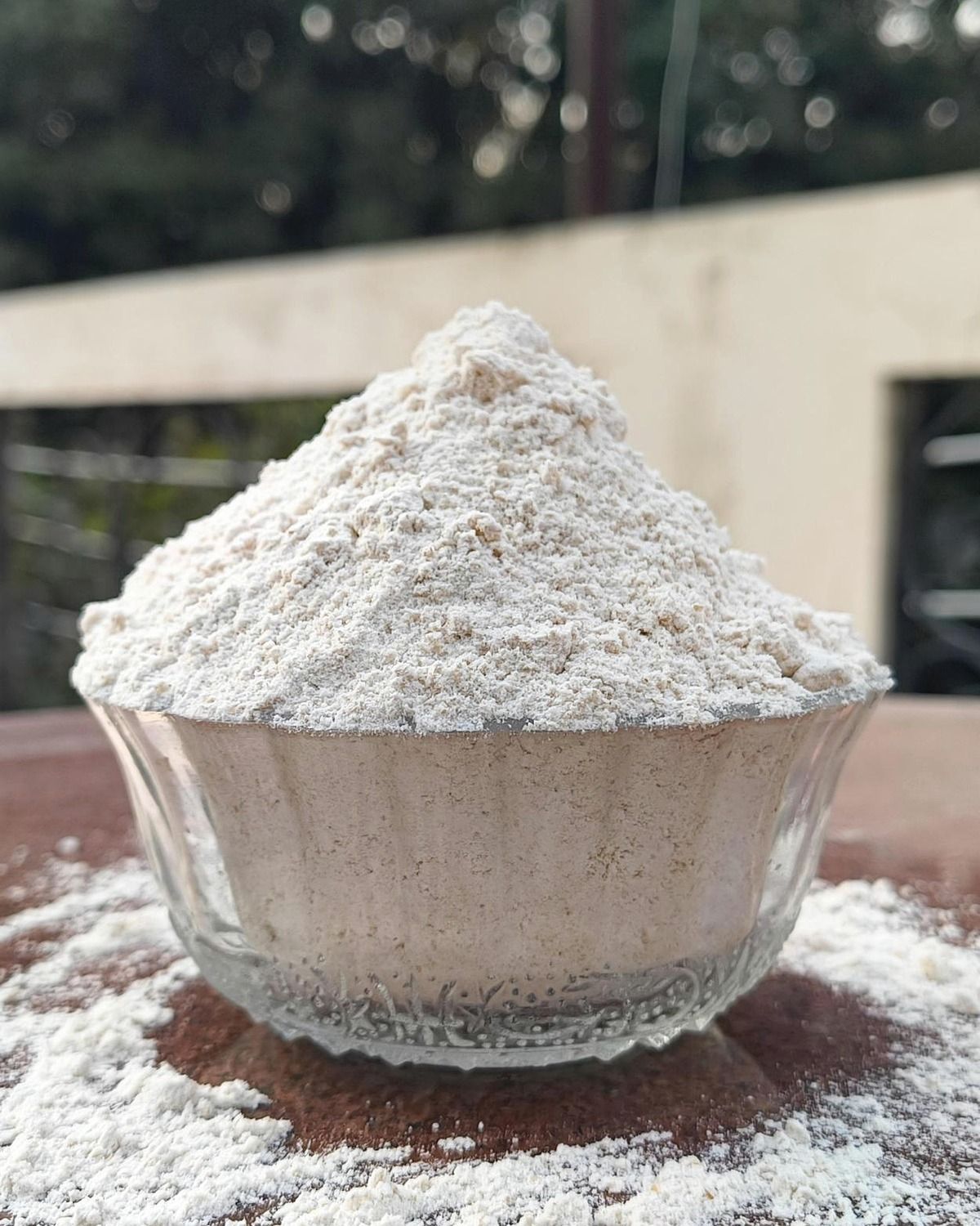 Stone-ground wheat atta mounded in glass bowl